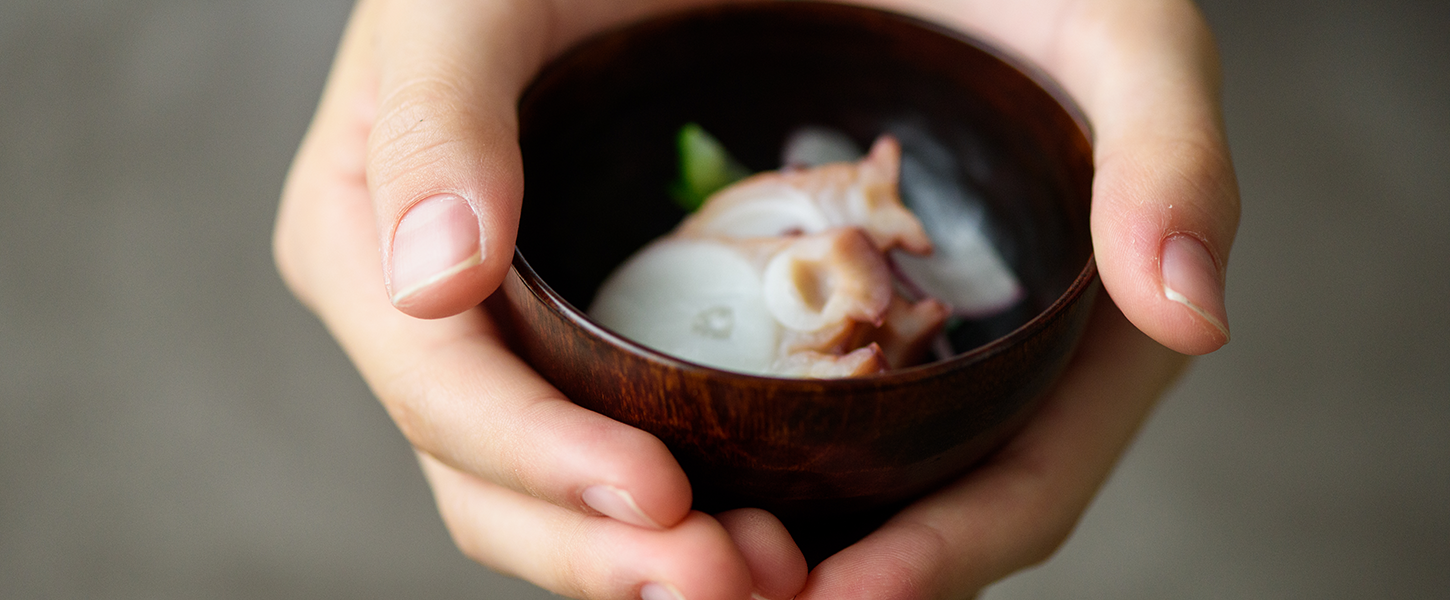 漆の椀を両手に持つ食卓の風景
